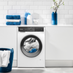 Lavadora en cuarto de lavado con toallas sobre encimera y en cesto de ropa sucia.