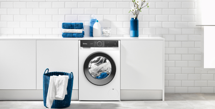 Lavadora en cuarto de lavado con toallas sobre encimera y en cesto de ropa sucia.